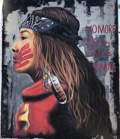 picture of a mural of a young Native American woman with a head band, wearing red and with a red hand print across her mouth